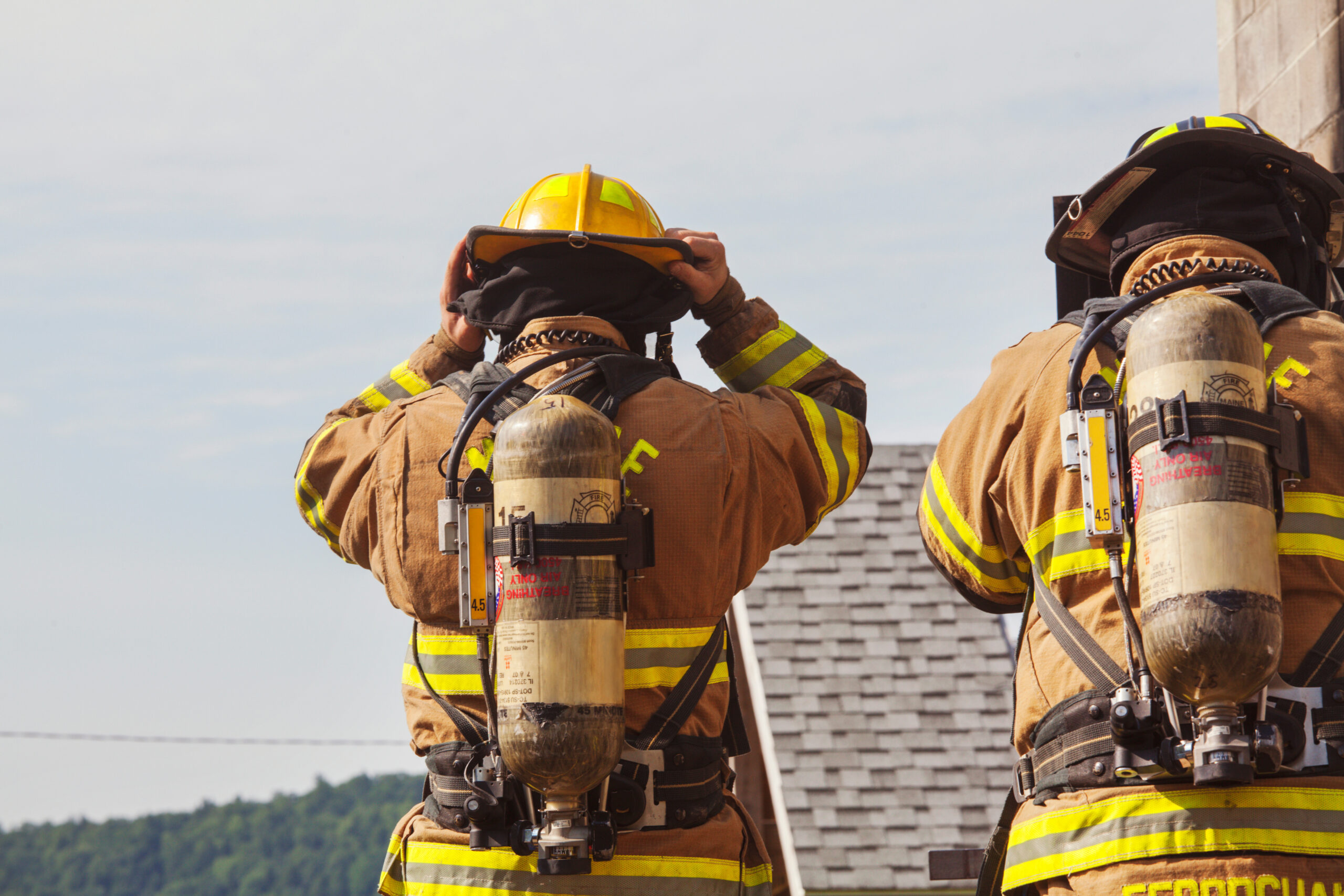 Rear view of firefighters carrying cylinders